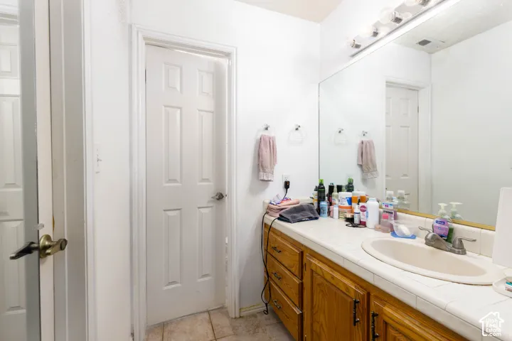 Wood-finish vanity with a tile countertop and an undermount sink