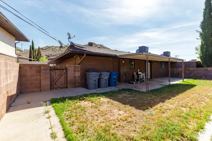 Brick exterior with a covered patio, concrete slab, and block wall fencing