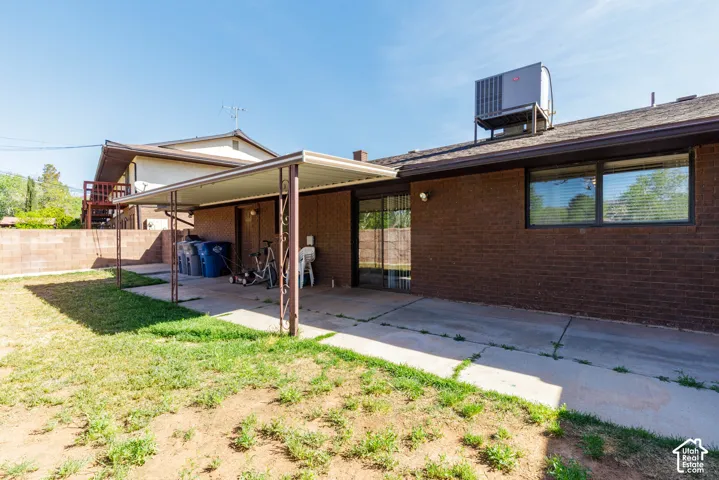 Brick exterior with a covered patio, concrete slab, and a grass area