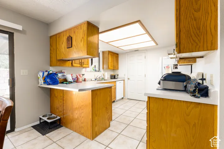 Kitchen featuring wood-finish cabinetry, light-toned countertops, and tile flooring