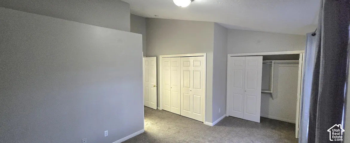 Vaulted ceilings, neutral-toned walls, and carpeted flooring