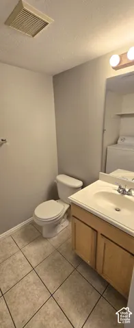 Bathroom featuring a light wood-finish vanity with an integrated sink, ceramic tile flooring, and a white toilet