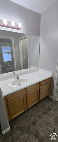 Bathroom vanity with light wood-finish cabinetry, white countertop, and integrated sink