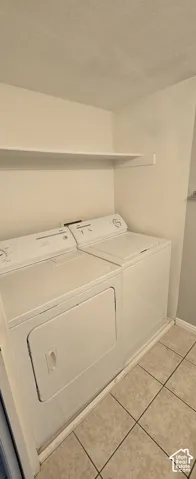 Dedicated laundry area featuring a washer and dryer, an overhead storage shelf, and tile flooring