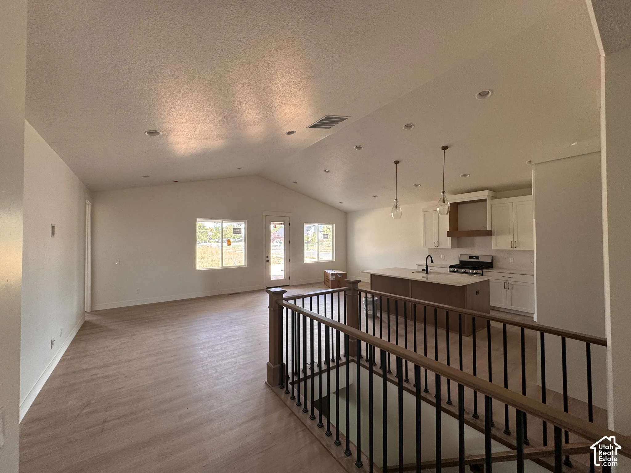 Open-concept living space with vaulted ceiling, recessed lighting, and wood-finish flooring throughout