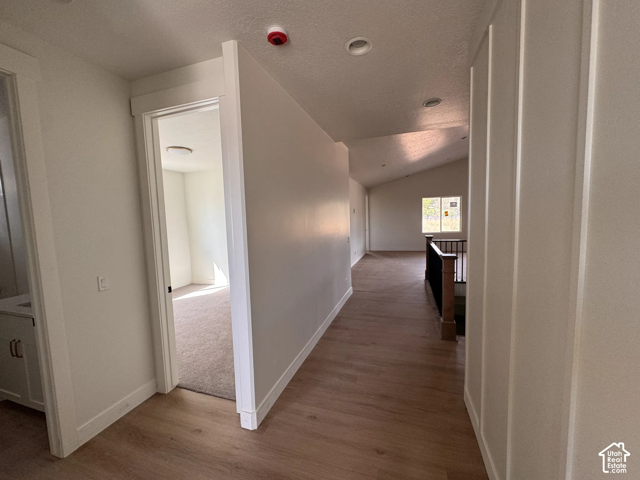 Bright hallway with wood-finish flooring, white trim, and recessed ceiling lighting