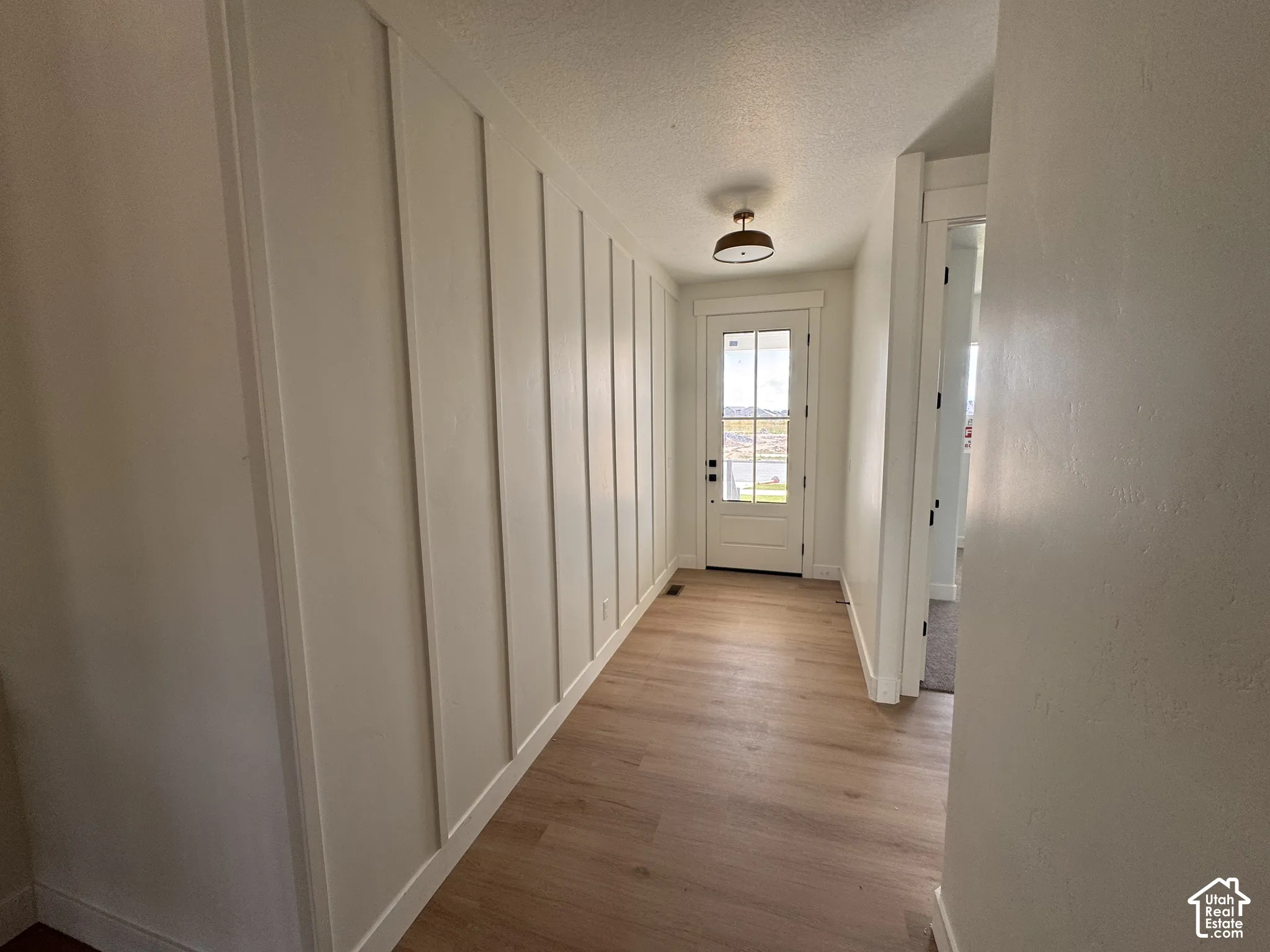 Entryway featuring board and batten accent wall, wood-finish flooring, and a flush-mount light fixture