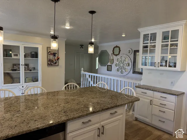 Kitchen featuring granite countertops, white cabinetry, and pendant lighting