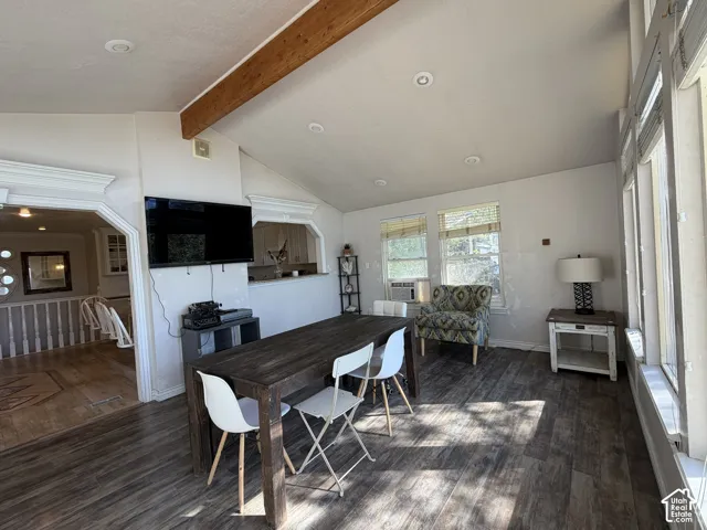 Vaulted ceiling with exposed wood beam, recessed lighting, wood-finish flooring, multiple windows, and decorative archways