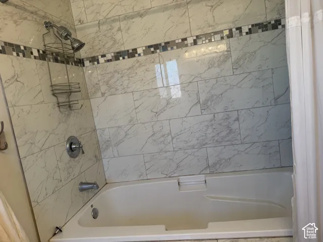 Bathtub with white subway tile surround, decorative mosaic tile accent, and polished chrome fixtures