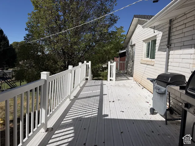 Expansive outdoor deck with white railing, featuring a light-colored brick exterior and a window