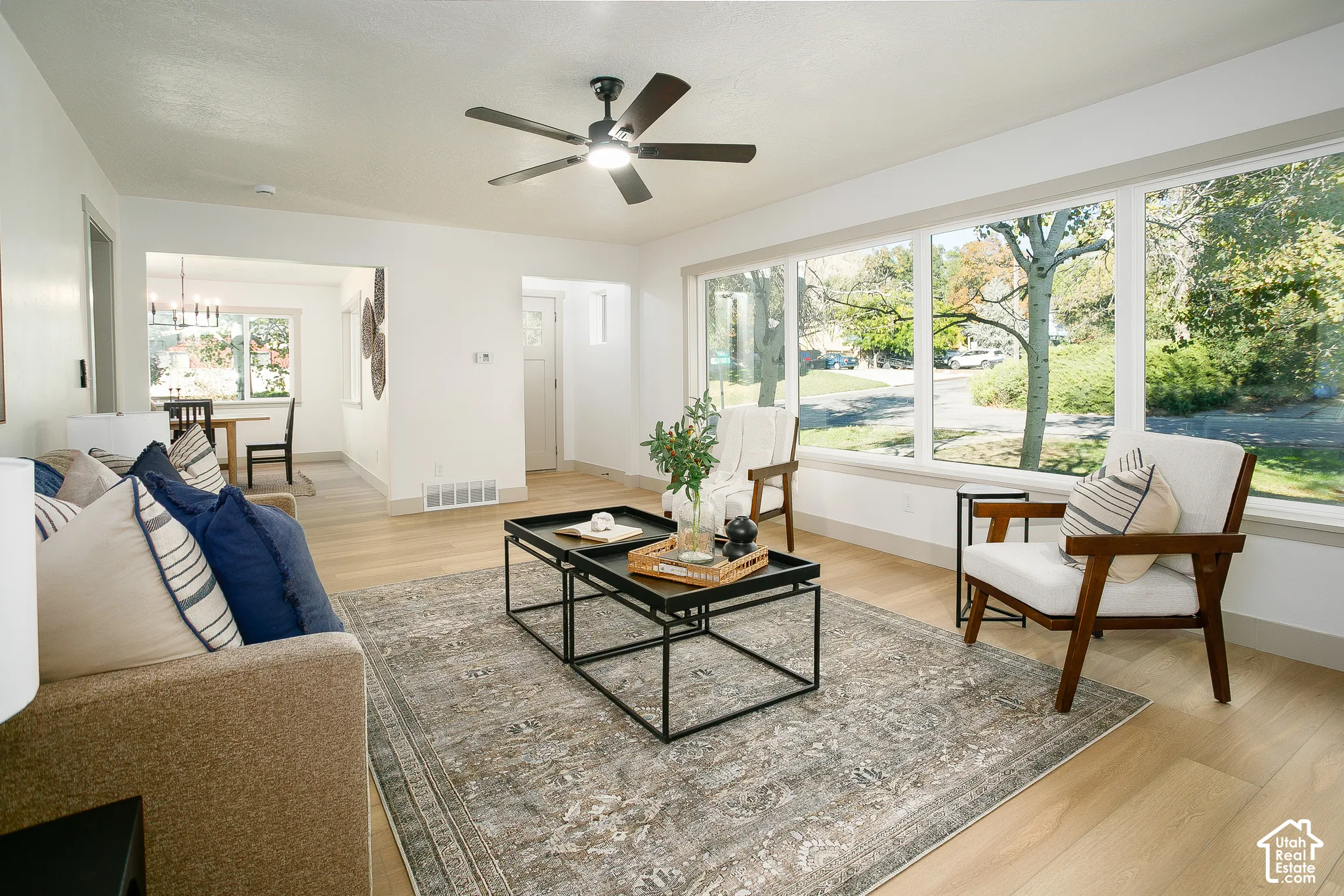 Expansive windows, light wood-finish flooring, recessed lighting, and a ceiling fan