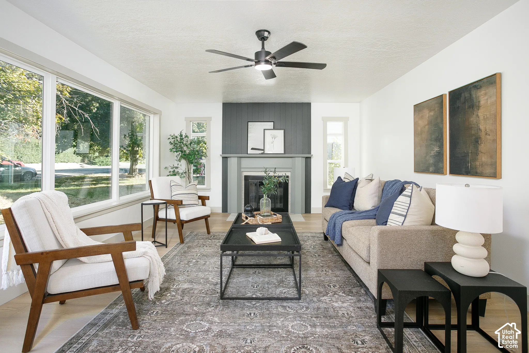 Light wood-finish flooring, a contemporary ceiling fan, and large windows