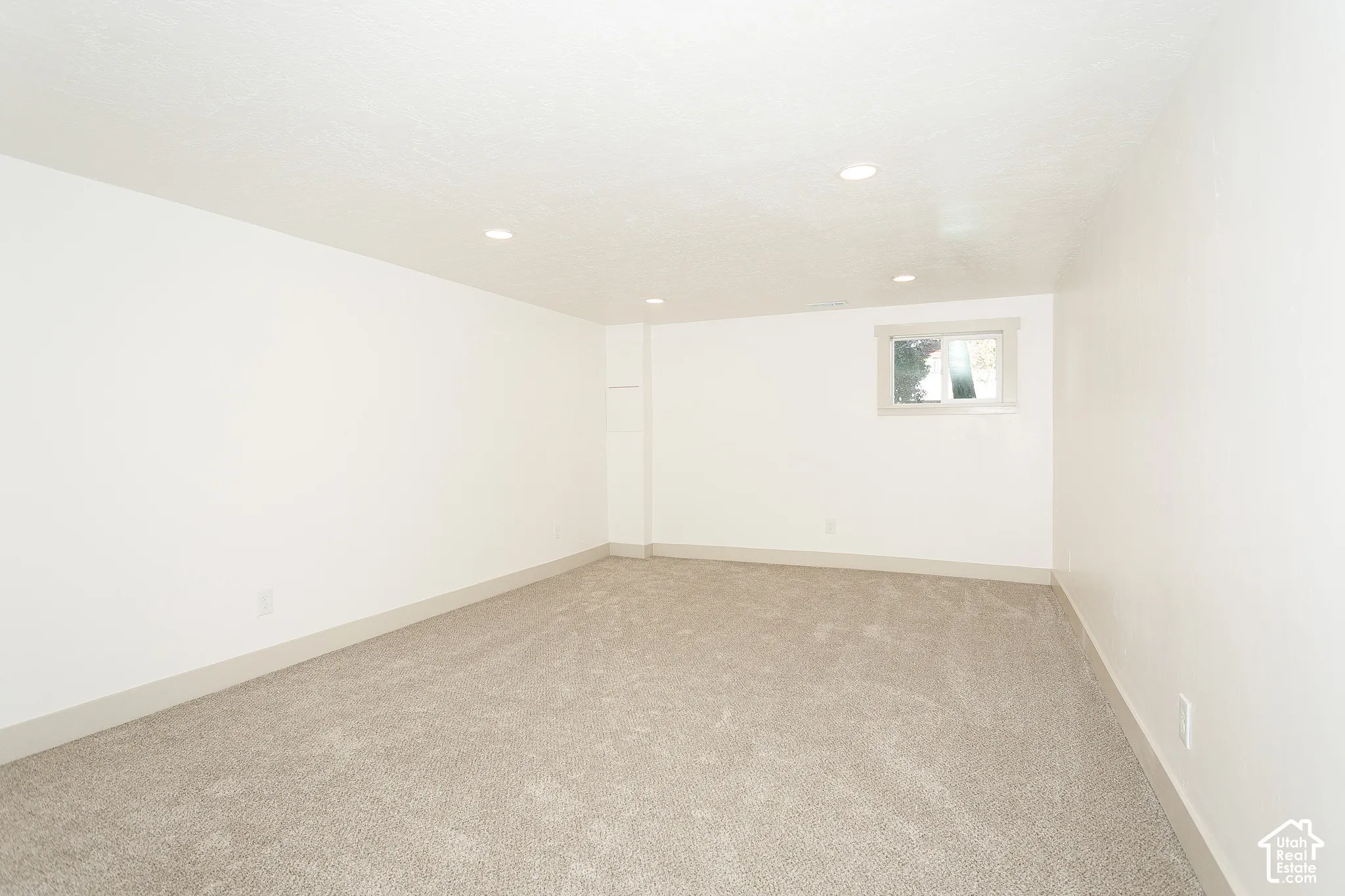Recessed lighting, light-toned carpeting, white walls, and a window with gray trim