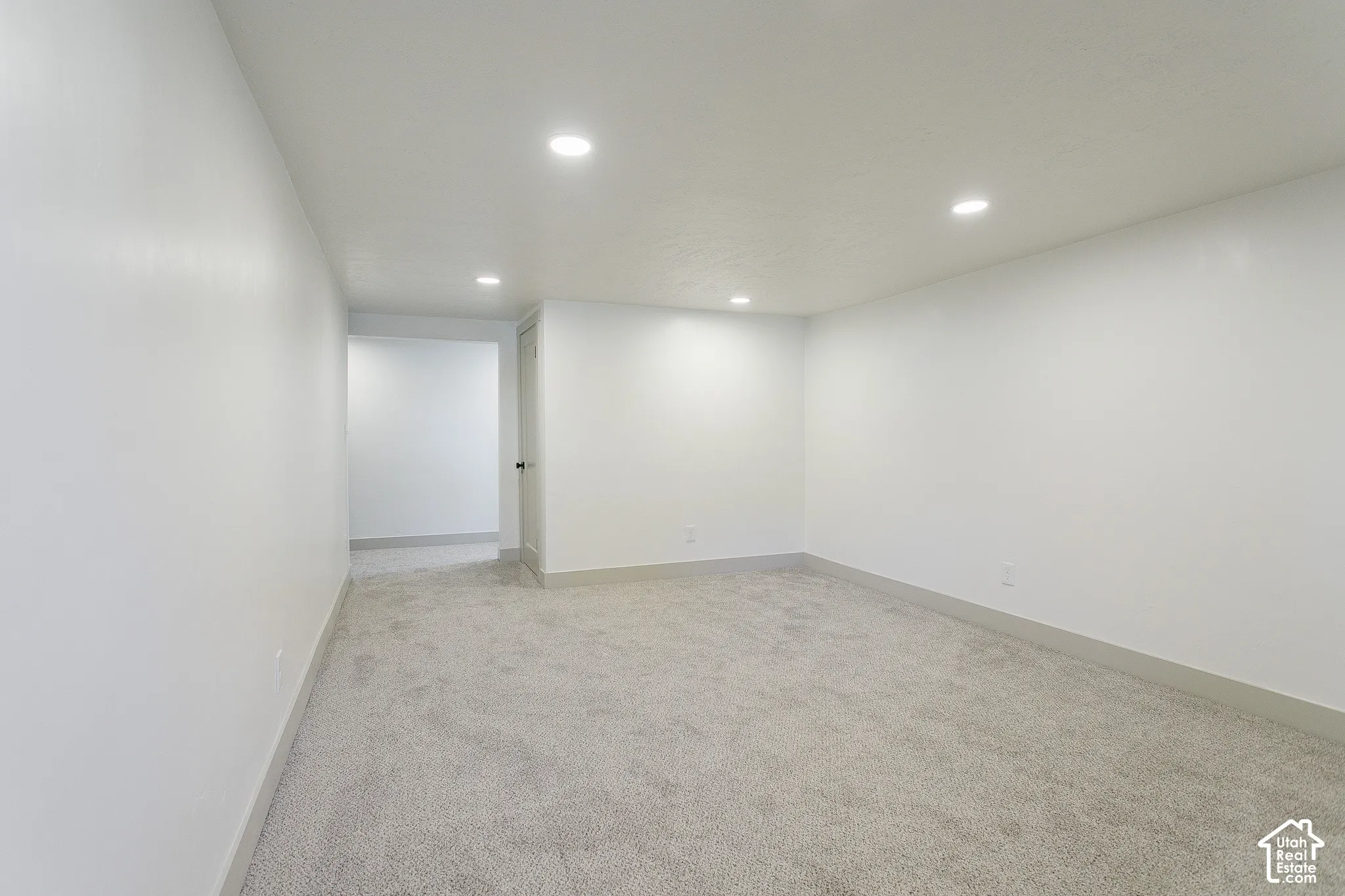 Recessed lighting illuminates the neutral carpet and white walls, complemented by a gray trim