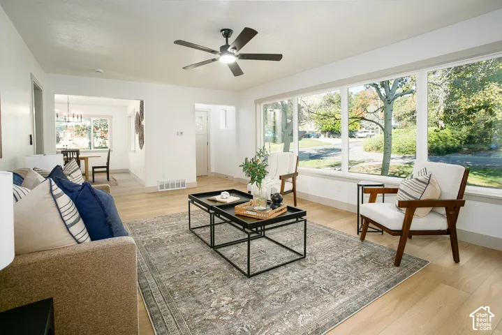 Expansive windows, light wood-finish flooring, recessed lighting, and a ceiling fan