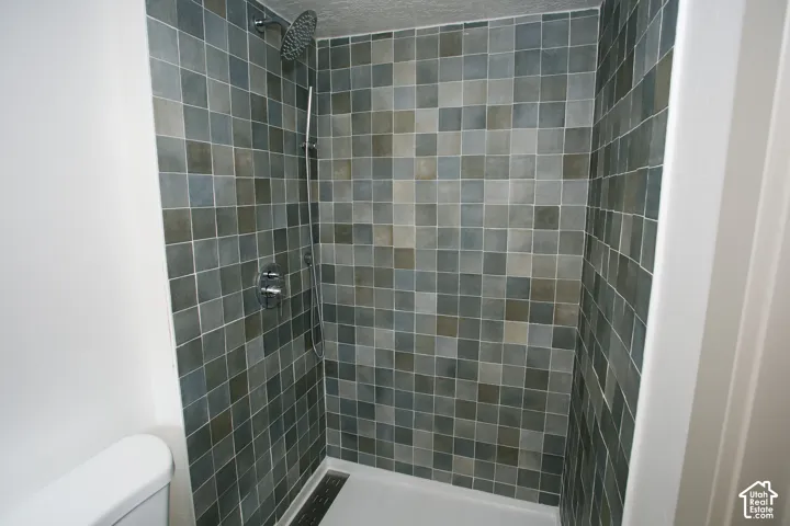 Tiled shower with a rainfall showerhead, handheld shower fixture, and a linear drain