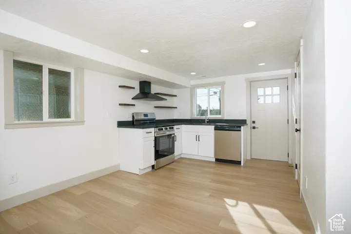 Kitchenette featuring wood-finish flooring, white cabinetry, dark countertops, and stainless steel appliances