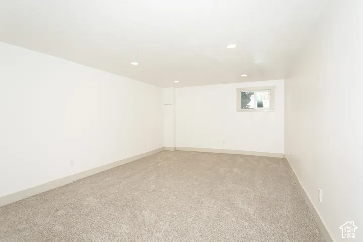 Recessed lighting, light-toned carpeting, white walls, and a window with gray trim