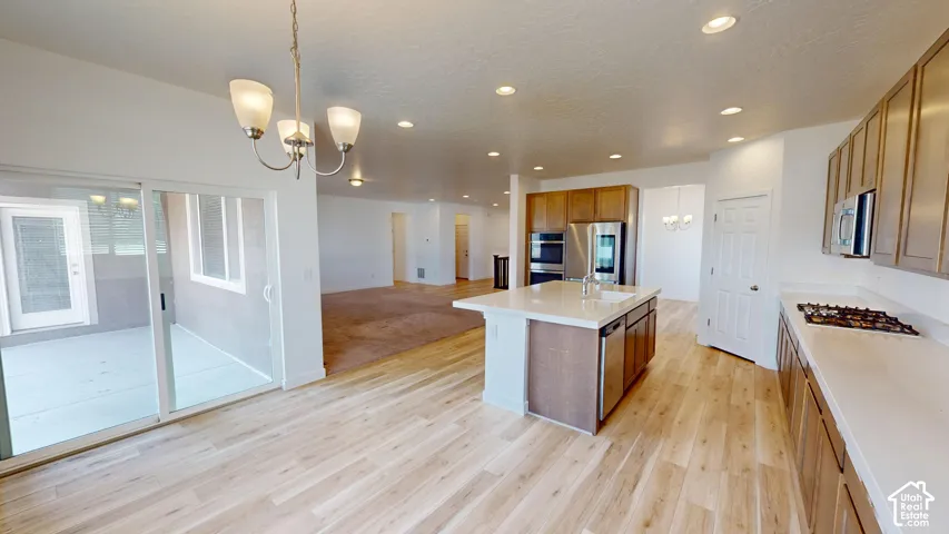 Kitchen with wood-finish flooring, light-toned cabinetry, light countertops, and a central island with an integrated sink