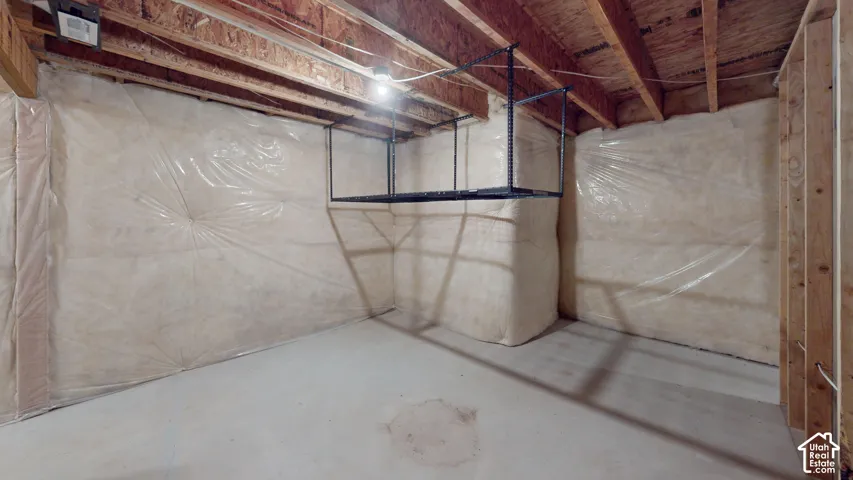 Unfinished basement space featuring exposed wood joists and concrete flooring