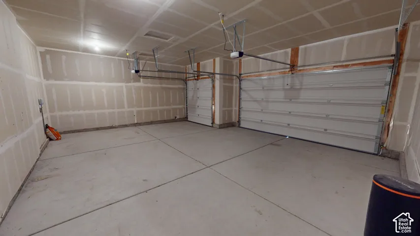 Spacious garage featuring a concrete floor, two garage doors, and overhead lighting