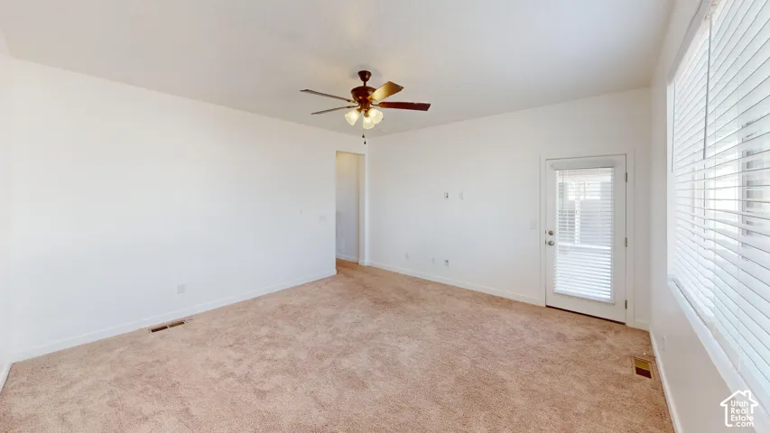Carpeted room with a ceiling fan, a glass-paneled door, and a window with blinds