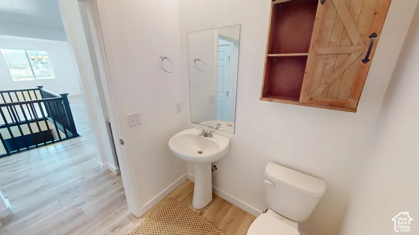 Pedestal sink with chrome faucet, wall-mounted mirror, and a wood-finish wall cabinet with a sliding barn door