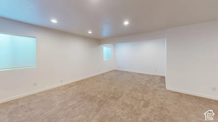 Recessed lighting illuminates this carpeted room with neutral-toned walls and multiple windows