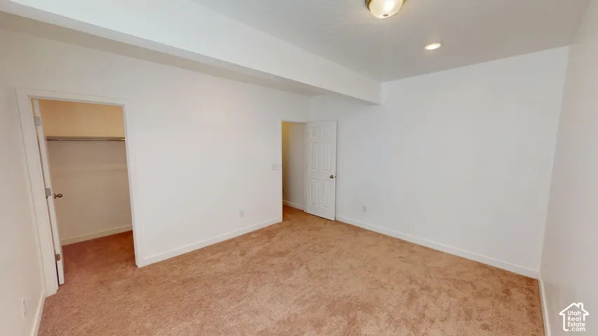 Carpeted flooring, white painted walls, overhead lighting, recessed lighting, and a closet with a built-in rod