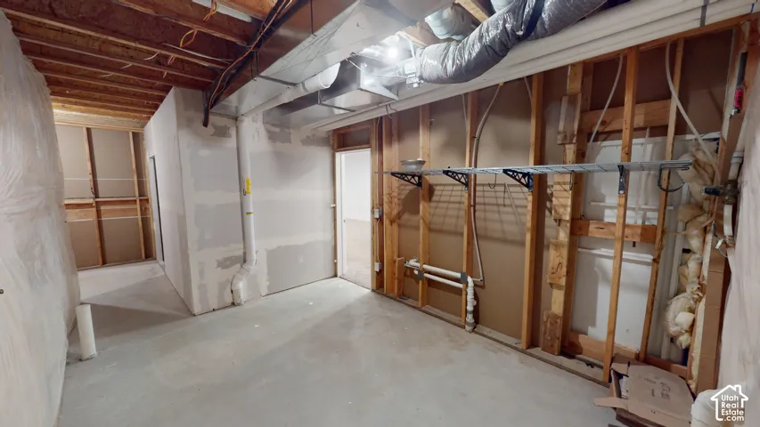 Concrete flooring, exposed ceiling joists, partially framed walls, installed drywall, and utility piping