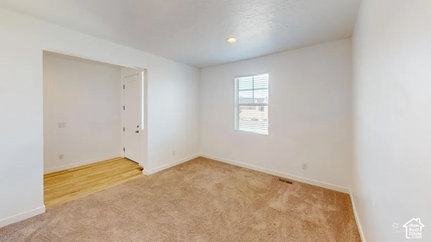 Recessed lighting, wood-finish flooring, broad window with blinds, light-toned carpeting, and a white interior door