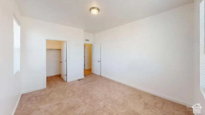 Neutral wall paint, carpet flooring, a window with blinds, a built-in closet with a hanging rod, and a semi-flush mount ceiling light fixture