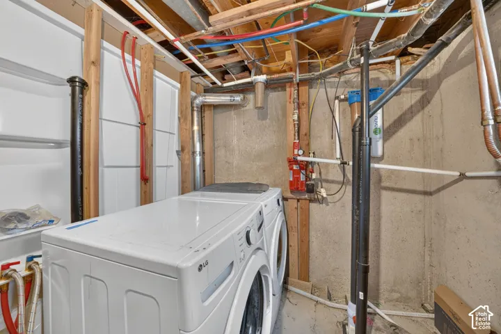 Utility area featuring exposed wood joists, concrete walls, and visible plumbing