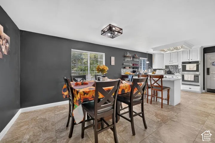 Open-concept dining area featuring tiled flooring, a window with blinds, and a contemporary ceiling light fixture