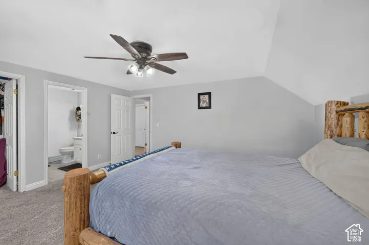 Vaulted ceiling with a ceiling fan, light gray wall paint, and gray carpet flooring