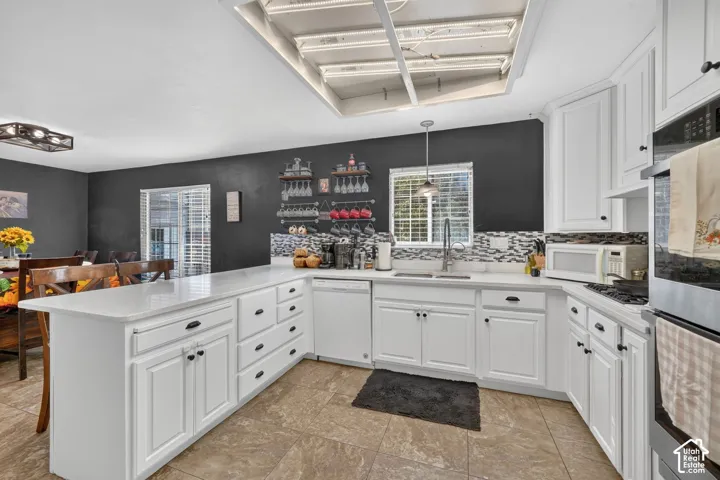 White cabinetry with dark hardware, stone countertops, a mosaic tile backsplash, and a built-in oven