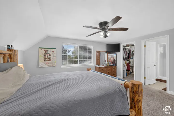 Angled ceiling lines, window with blinds, ceiling fan, carpet flooring, and open closet space