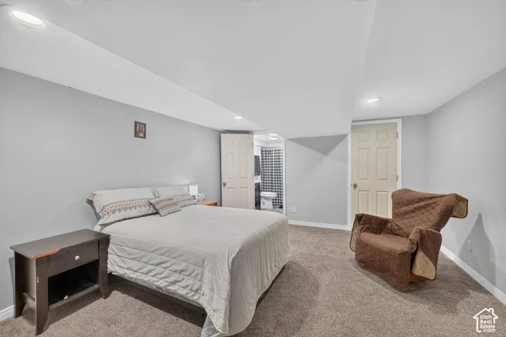 Recessed ceiling lighting, light gray walls, carpeted flooring, and a flat panel door