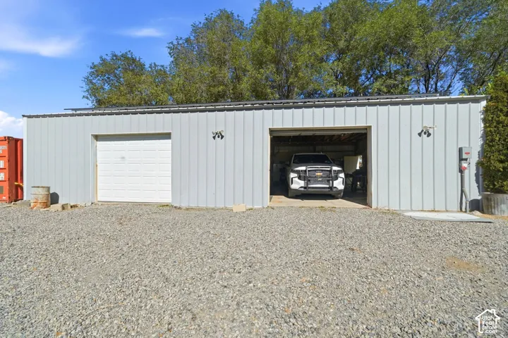 Corrugated metal building featuring two garage bays, one with a roll-up door and another open