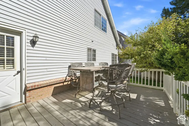 Spacious deck with white railing, brick foundation accent, and white siding
