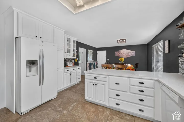Contemporary kitchen featuring white cabinetry, a large center island with counter seating, a built-in dishwasher, and wood-finish tile flooring