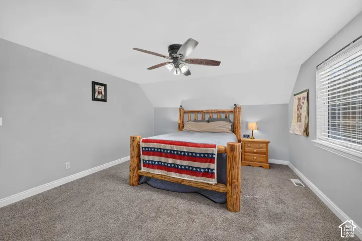 Carpeted flooring with white trim, vaulted ceiling, and ceiling fan