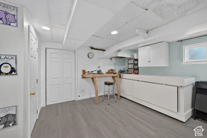 Recessed lighting, wood-finish flooring, white bi-fold doors, built-in cabinetry, and a window