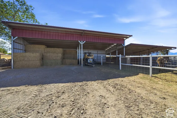 Metal-framed covered structures with corrugated roofing, gravel flooring under cover, and fenced enclosures