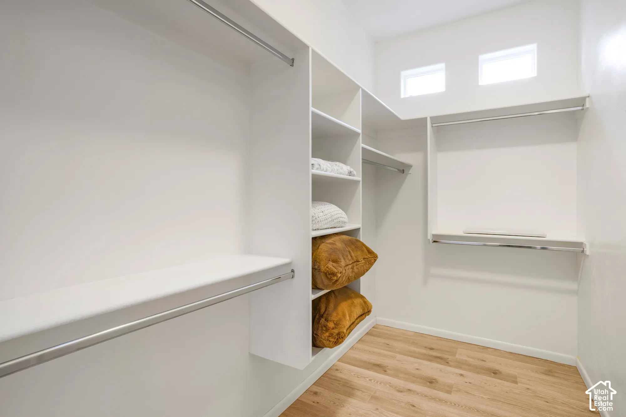 Custom closet organization system with wood-finish flooring, multiple shelving units, and integrated hanging rods