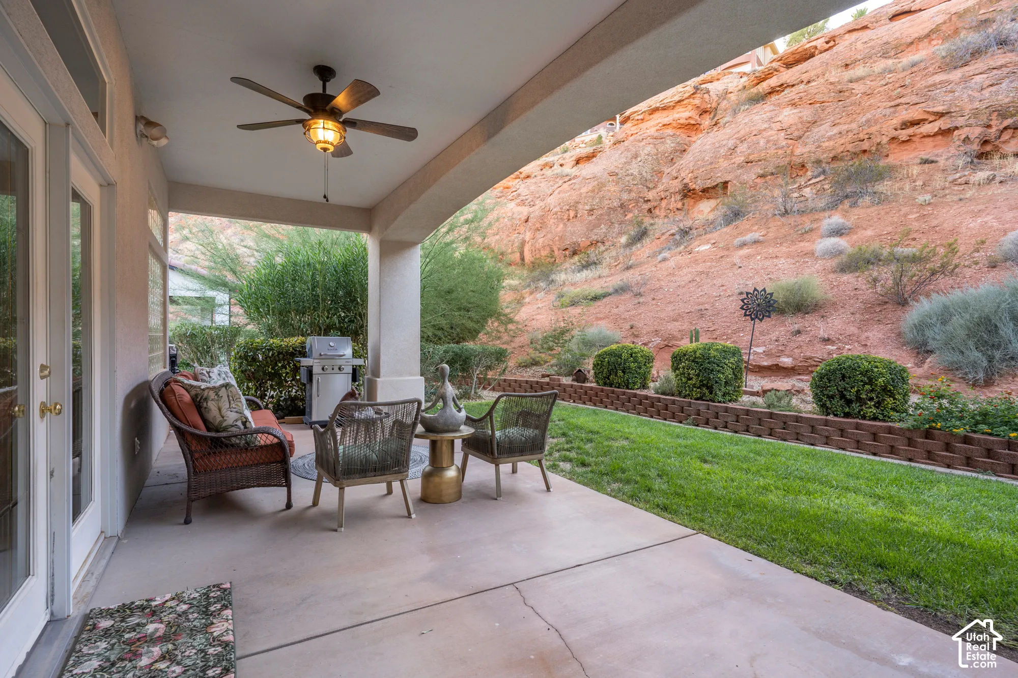Covered patio featuring a ceiling fan, concrete flooring, and direct access to a manicured lawn