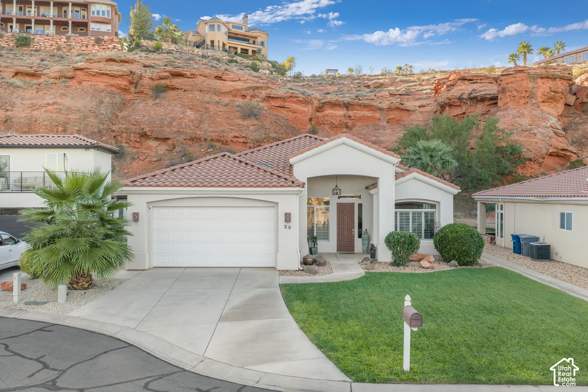 Stucco exterior residence featuring a tile roof, an integrated garage, and a concrete driveway
