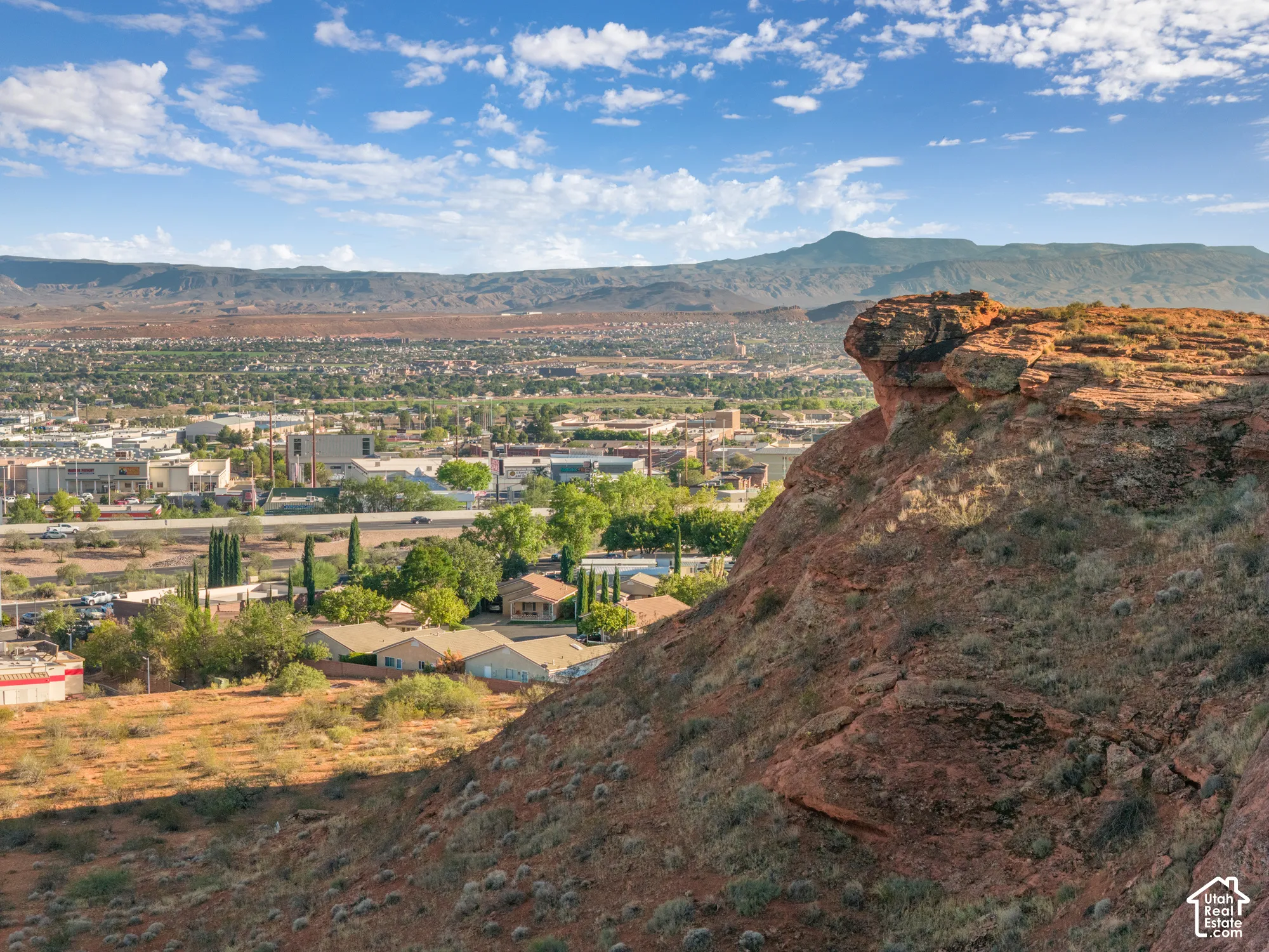 Expansive aerial of a developed community with surrounding natural rock formations and distant mountains