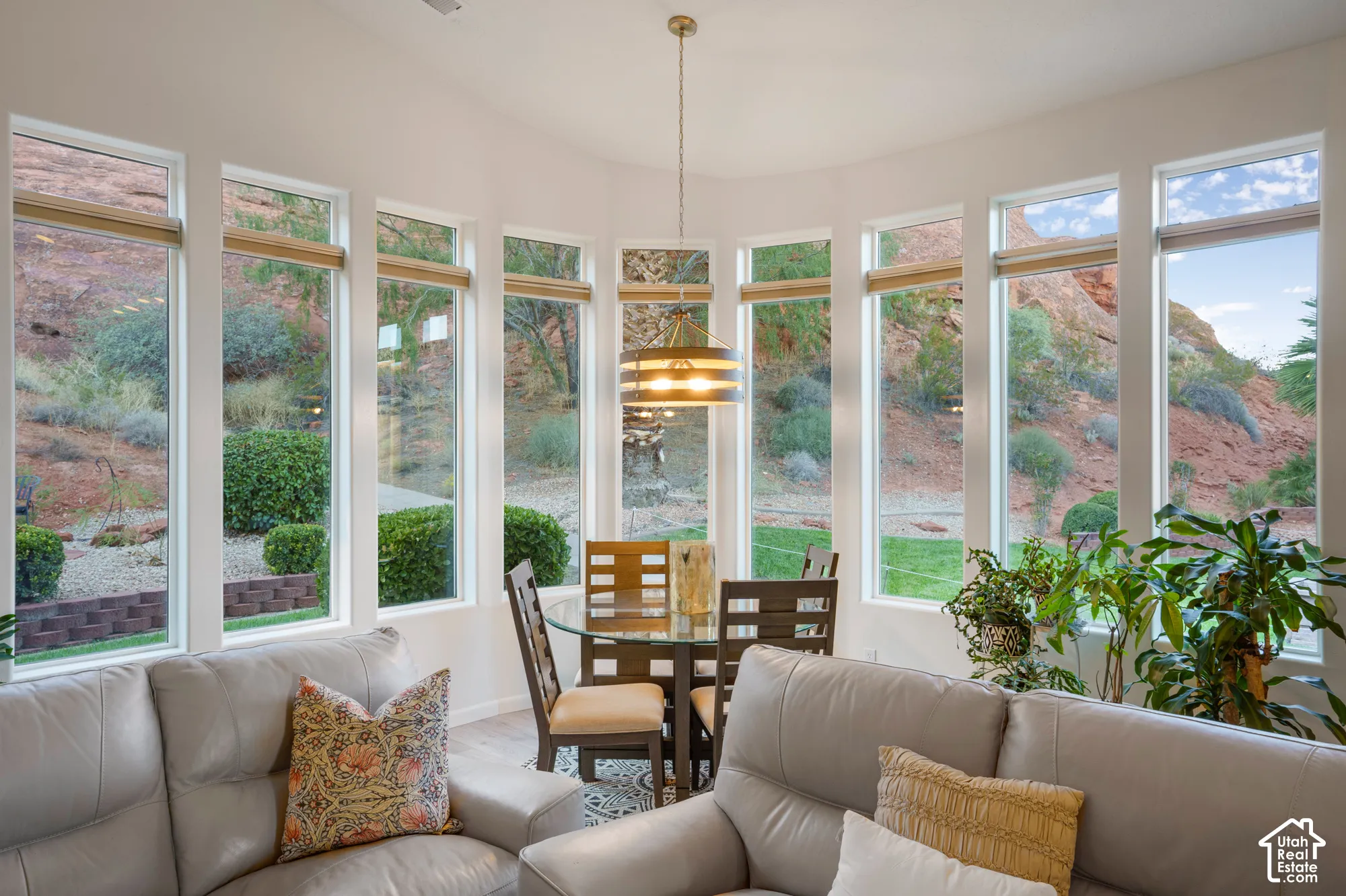 Expansive bay window design with multiple vertical windows, light-toned wall finishes, and a circular dining area with a brass chandelier